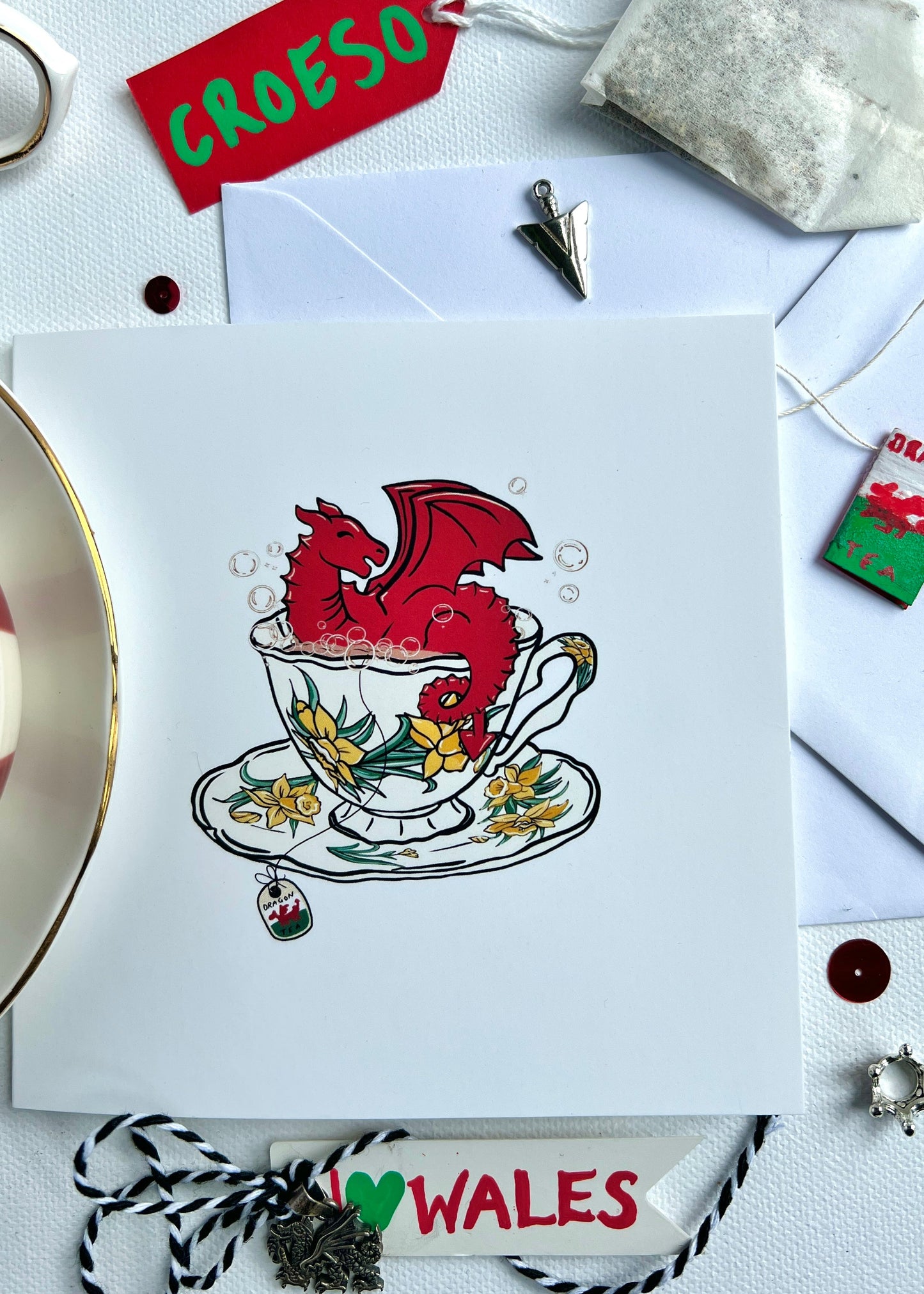 Card with a red welsh dragon in a teacup on a white background